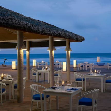 An outdoor dining area with tables and chairs, overlooking the ocean.
