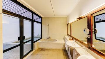 A modern bathroom with a large bathtub, two sinks, and a large mirror.