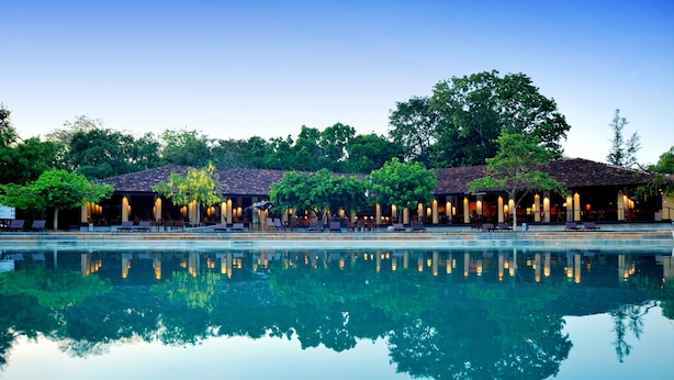 A pool with a reflection of a building and trees. - Habarana Village by Cinnamon (Habarana)