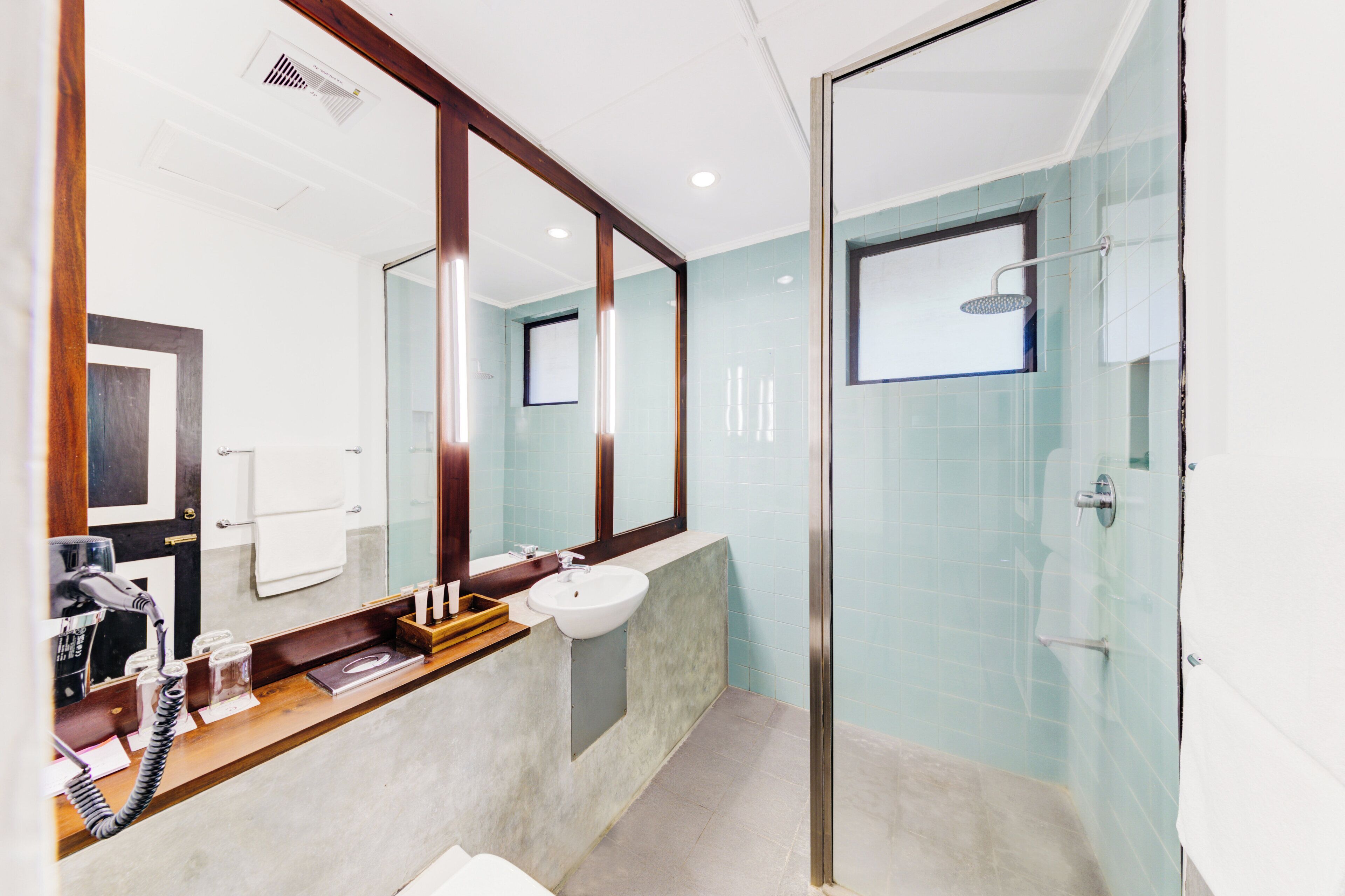 A modern bathroom with a large mirror, a sink, and a shower area.