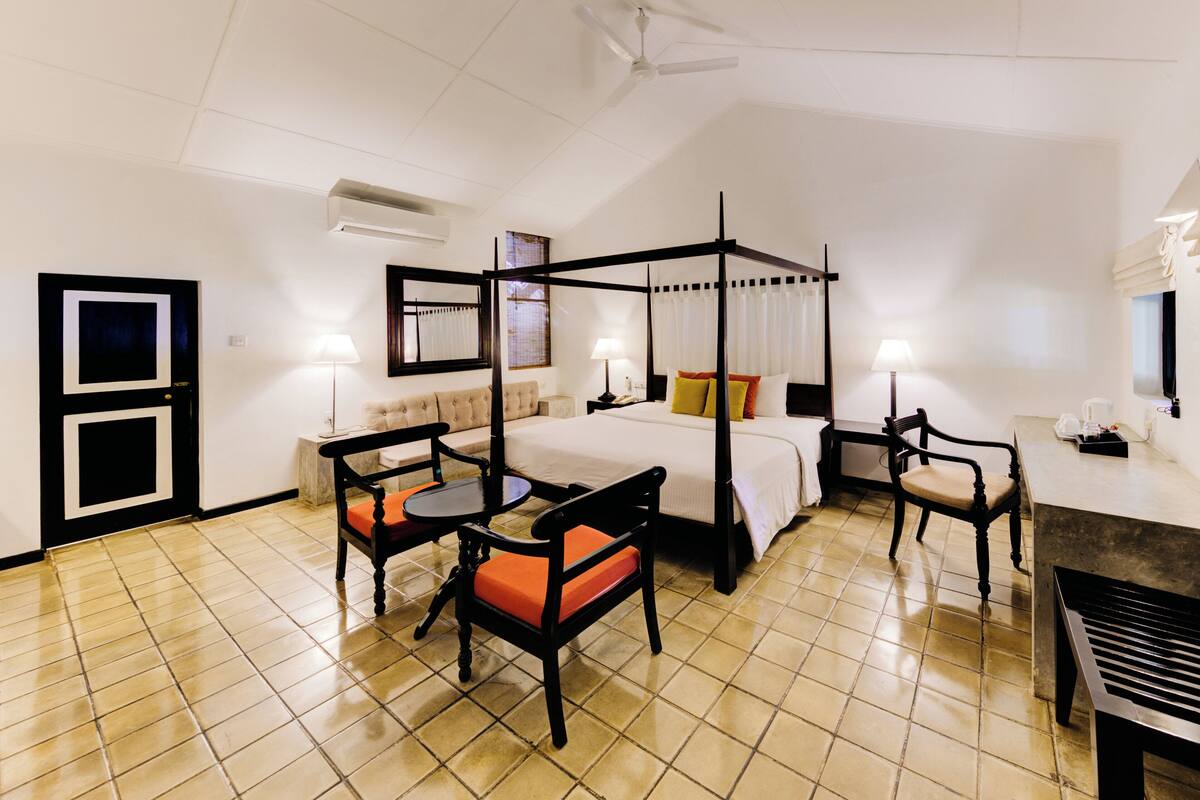 Un lit à baldaquin, un canapé, deux fauteuils, une petite table et un banc.