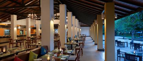 A spacious restaurant with long tables, high ceilings, and a view of the outdoor area.
