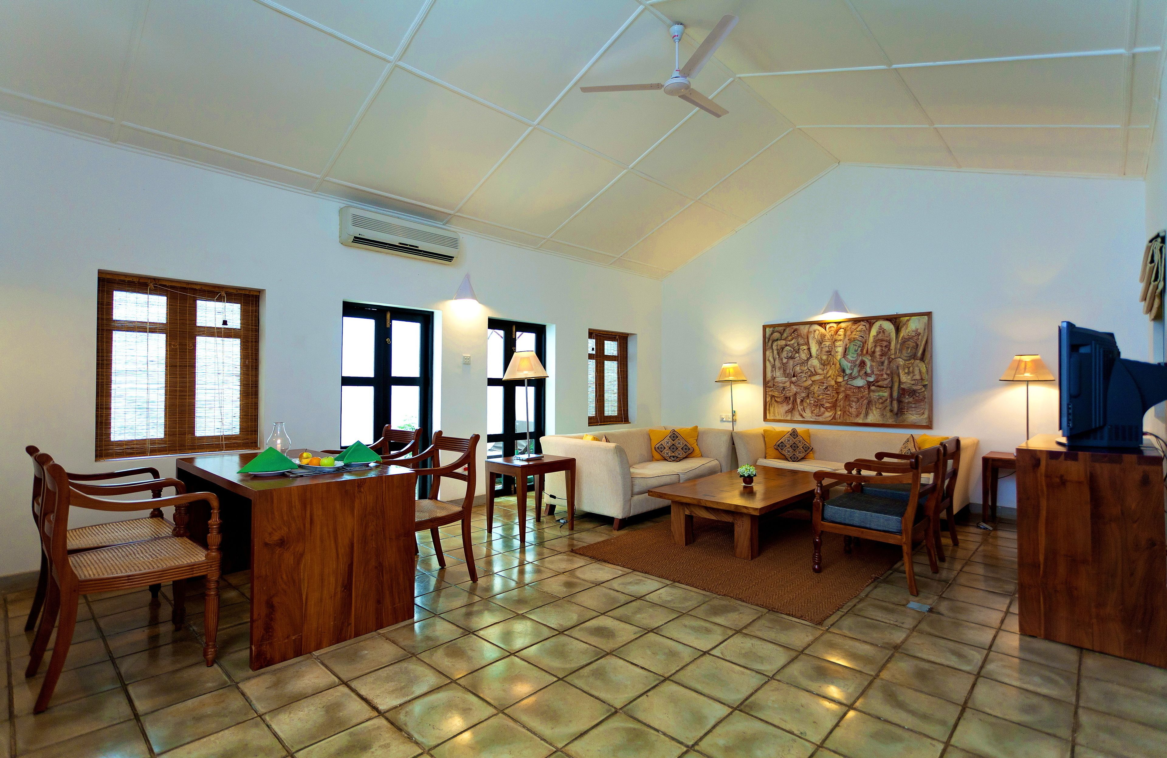 A spacious living area with a dining table, chairs, sofas, and a ceiling fan.