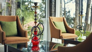 A room with two brown armchairs, a glass coffee table, and two hookahs. - Jetwing St. Andrew's (Nuwara Eliya)