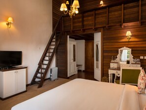 A bedroom with a bed, a TV, a dresser, a chair, a desk, a mirror, a radiator, a staircase, and wall-mounted lamps. - Jetwing St. Andrew's (Nuwara Eliya)