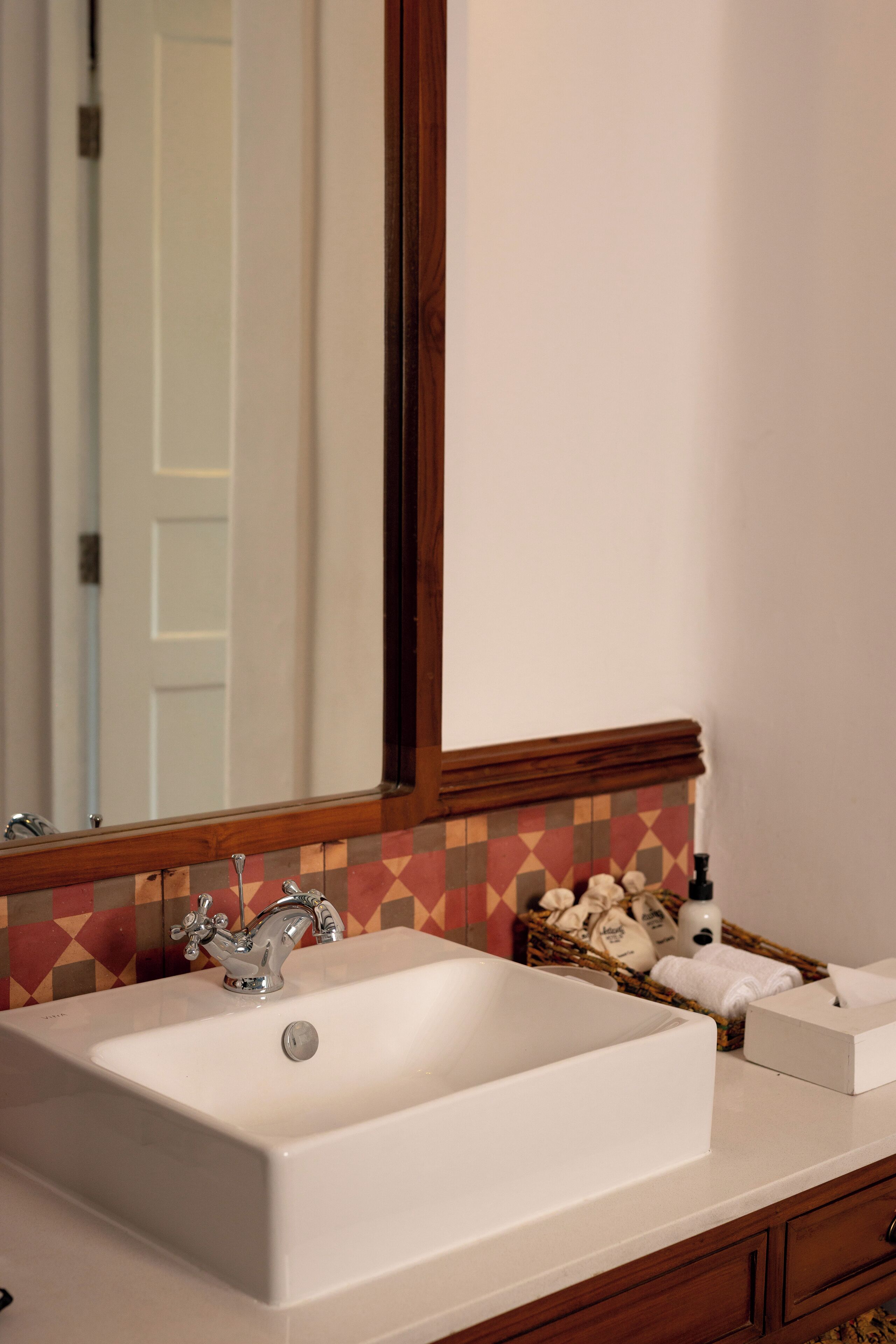 A bathroom with a white sink, a mirror, and a tiled backsplash.