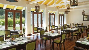 A dining area with multiple tables and chairs, large windows, and hanging lanterns. - Jetwing St. Andrew's (Nuwara Eliya)