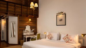 A bedroom with a bed, bedside tables, a dresser, a mirror, and a hanging light fixture. - Jetwing St. Andrew's (Nuwara Eliya)