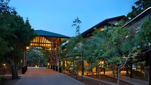 A modern building with a covered walkway, trees, and benches. - Cinnamon Wild Yala (Kirinda)