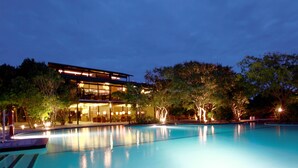 A swimming pool with a modern building in the background. - Cinnamon Wild Yala (Kirinda)