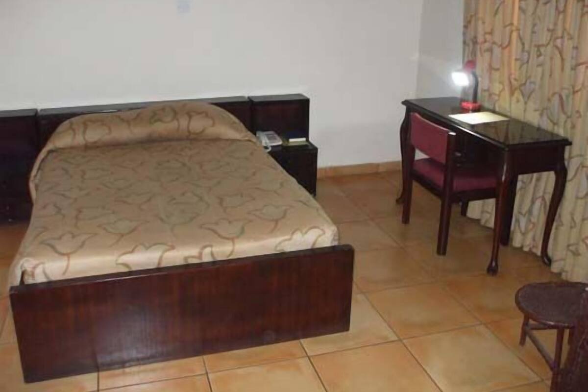 A bedroom with a bed, bedside table, and a desk with a chair.