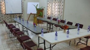A conference room with a long table, red chairs, and water bottles. - Coconut Grove Miners Lodge (Obuasi)