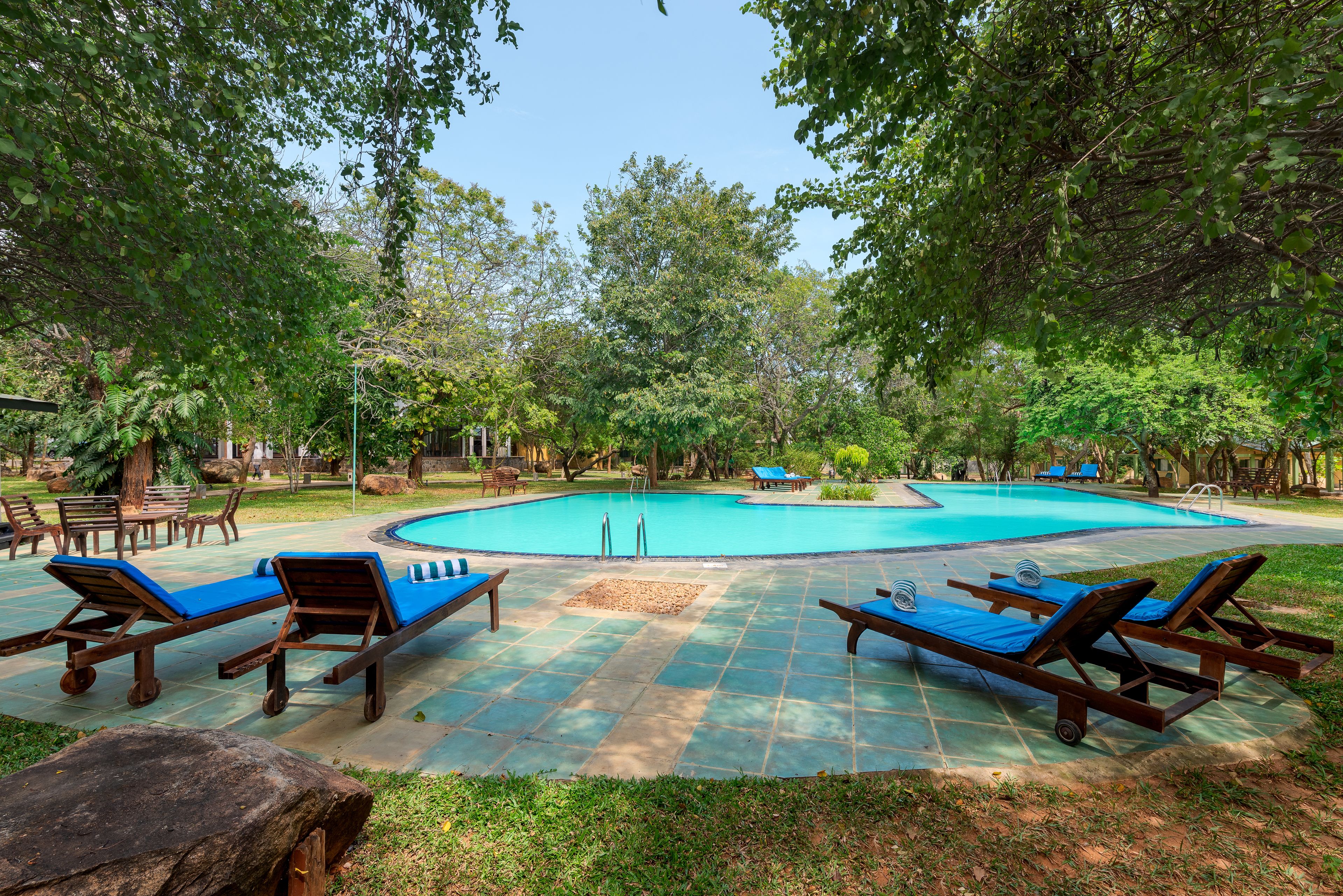 Un área de piscina con tumbonas de madera y un deck de baldosas.