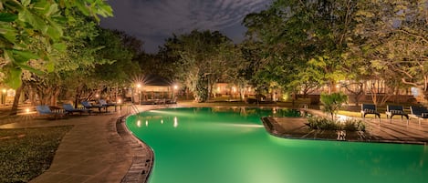 Una piscina al aire libre, sombrillas, sillones reclinables de piscina