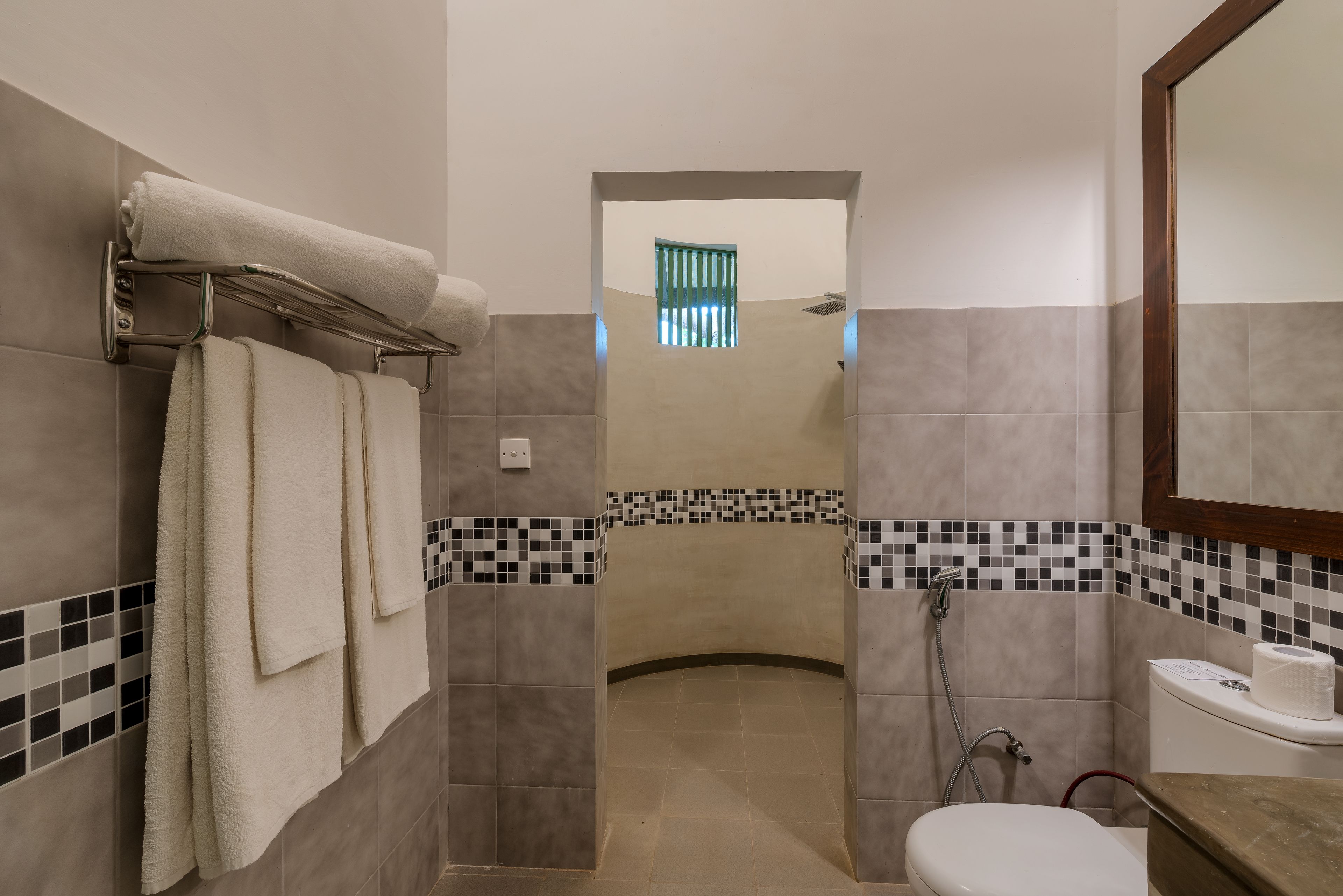 Een badkamer met douche, toilet en handdoekrek.