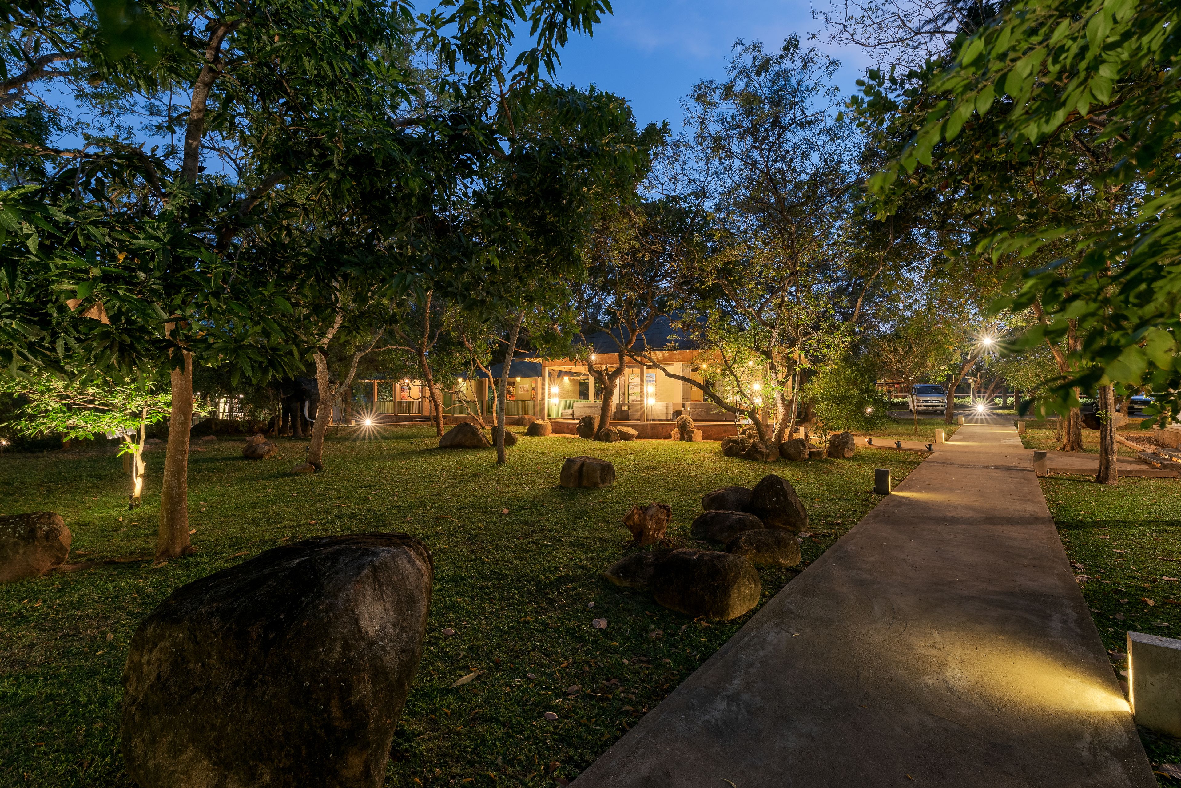A pathway leading to a building surrounded by trees and rocks.