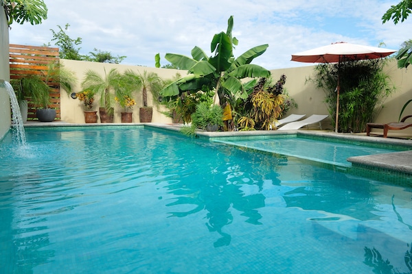 Una piscina al aire libre, sillones reclinables de piscina