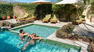 Relax by the serene pool surrounded by lounge chairs and umbrellas.