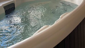 Un jacuzzi en una habitación con ventana, estantes y puerta.