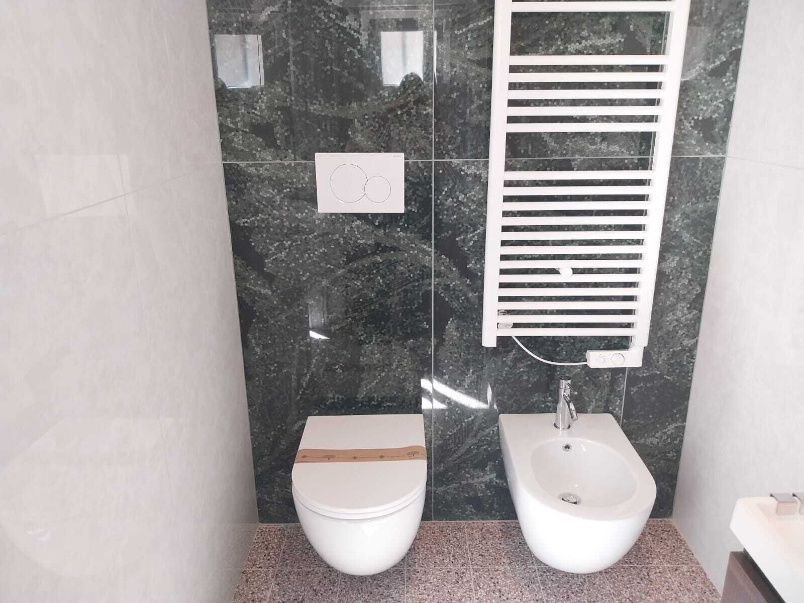 Un baño moderno con inodoro, bidé y un perchero para toallas.