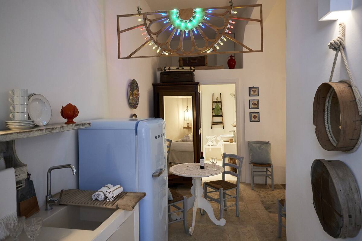 Une chambre d’hôtel compacte dotée d’une kitchenette, d’un petit coin repas et d’une salle de bain visible à travers une porte ouverte.