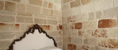A room with a stone wall bed, white linens, and a wooden headboard.
