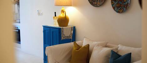 A living room with a white sofa, a blue cabinet, a yellow lamp, and two decorative plates on the wall.