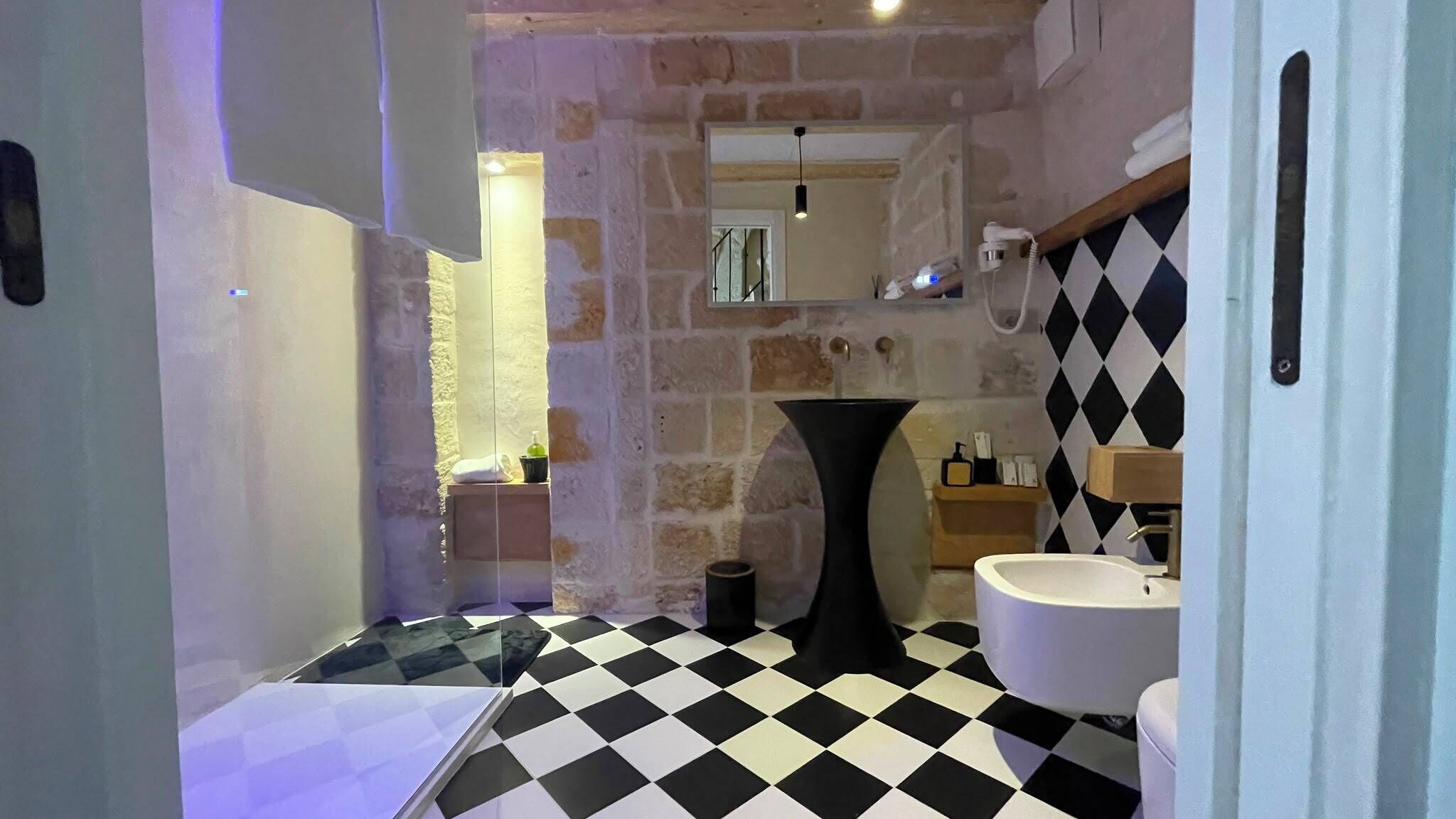 A bathroom with a checkered floor, a sink, and a mirror.
