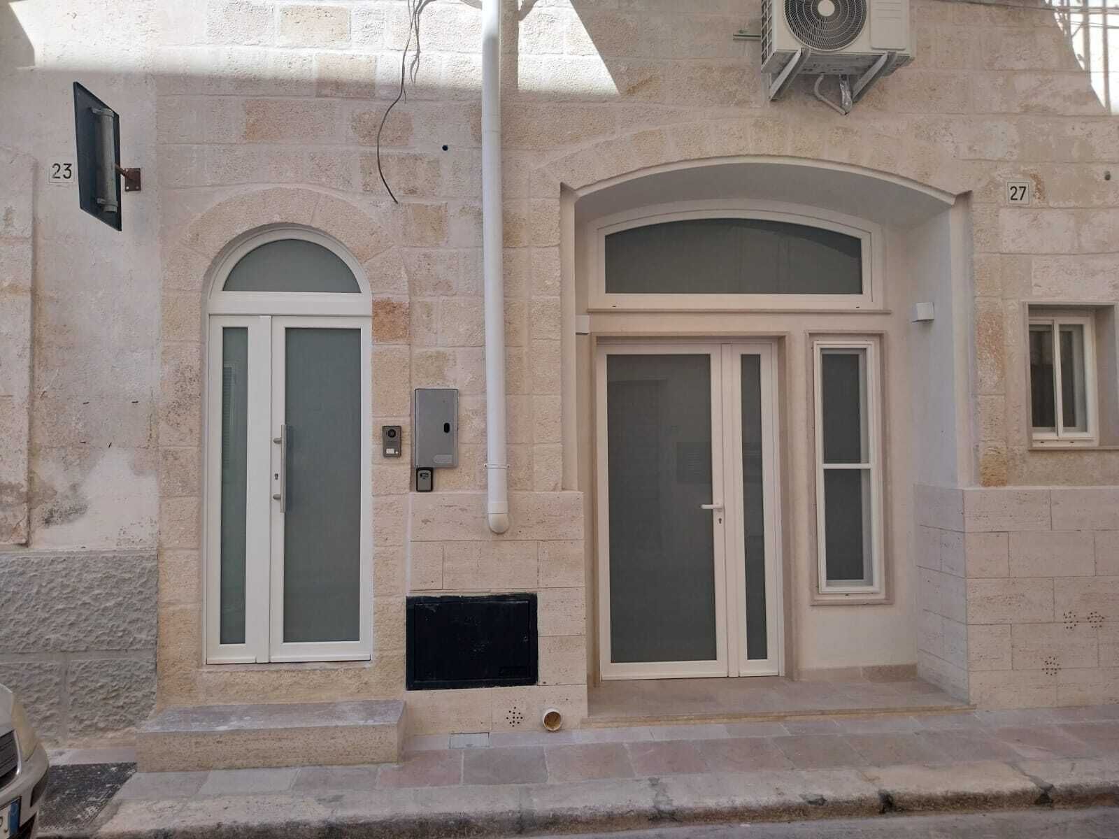 A building with two arched doorways, a small window, and a utility box on the wall.