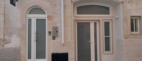 A building with two arched doorways, a small window, and a utility box on the wall.