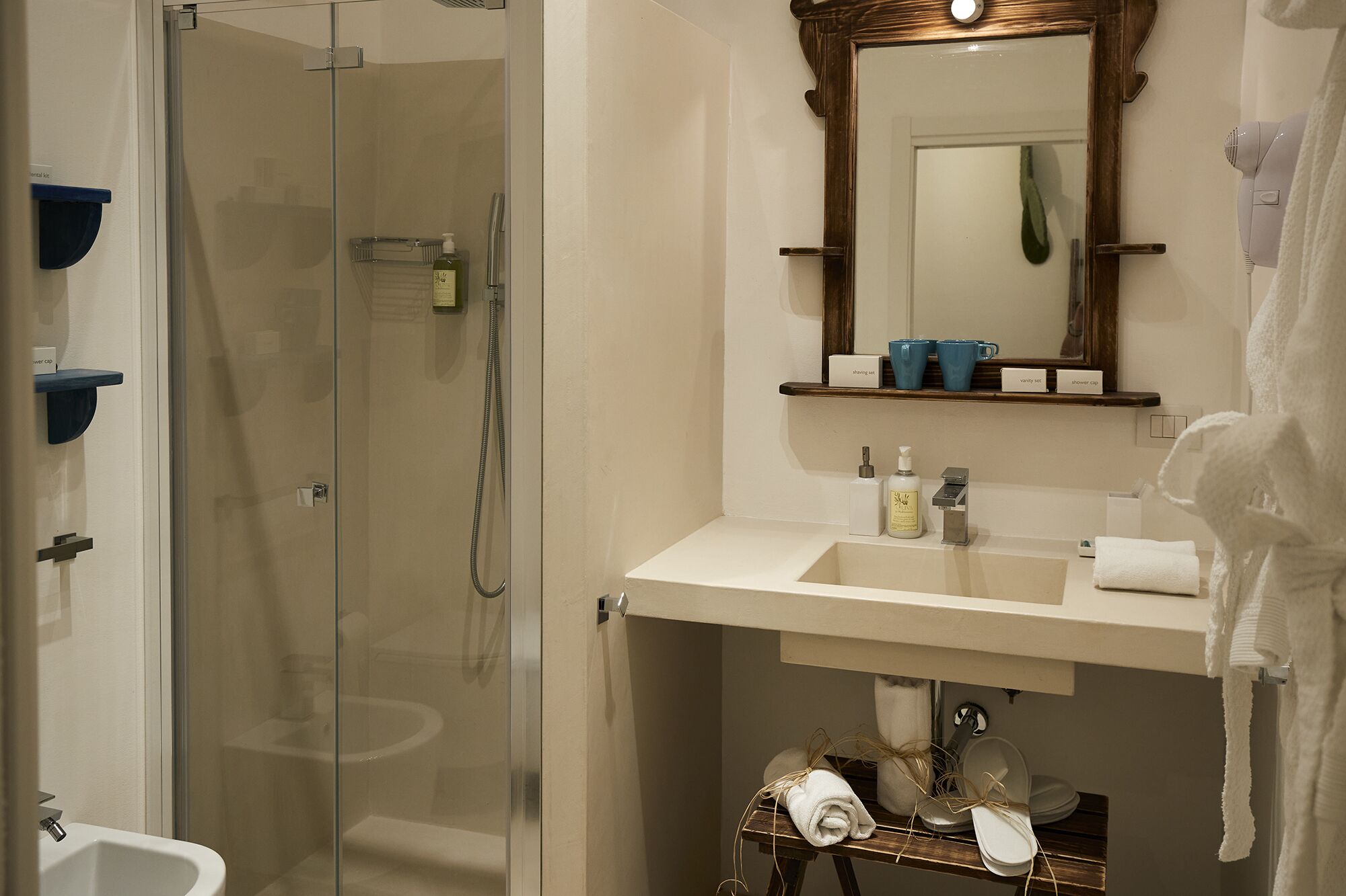 Un baño con ducha de vidrio, lavamanos con espejo y perchero con toallas.