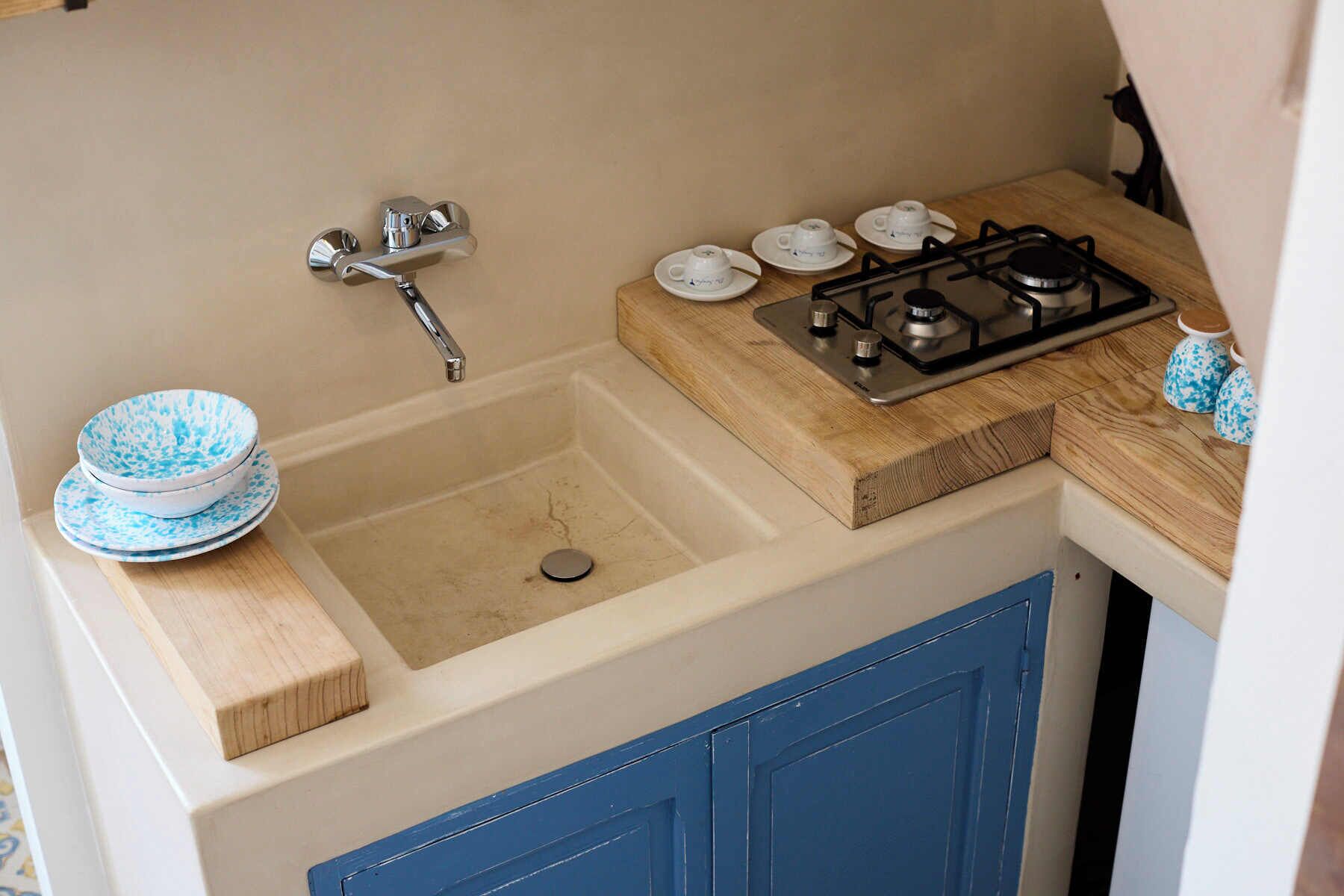 A compact kitchenette with a sink, faucet, and stove.