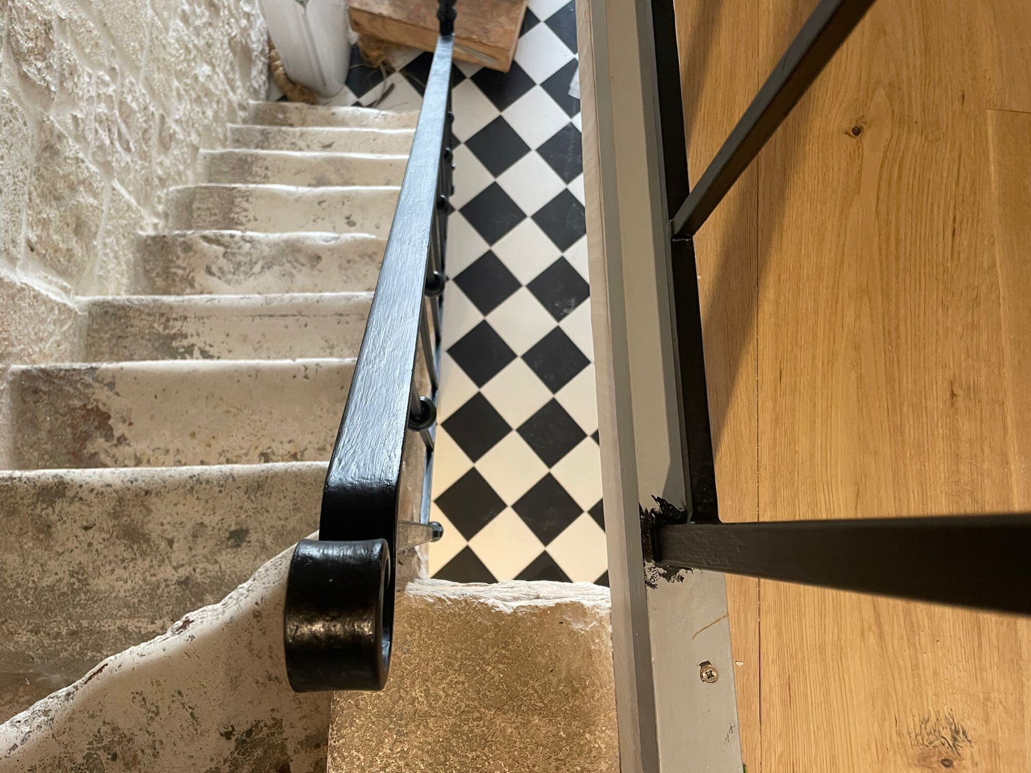 A staircase with a black handrail, a checkered floor, and a wooden door.