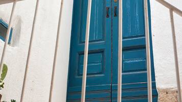 Una puerta azul con dos pomos, paredes blancas y una reja de metal.