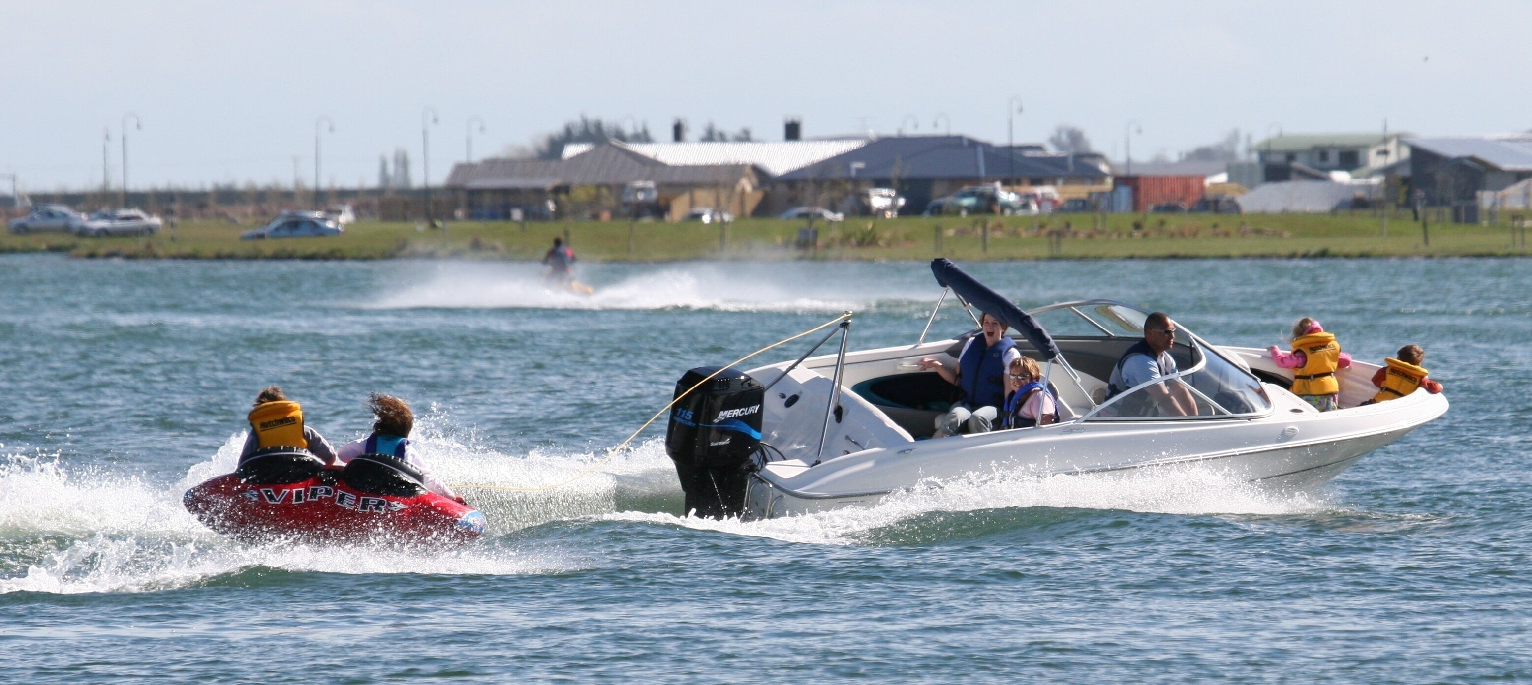 A speedboat with passengers wearing life jackets on a body of water.
