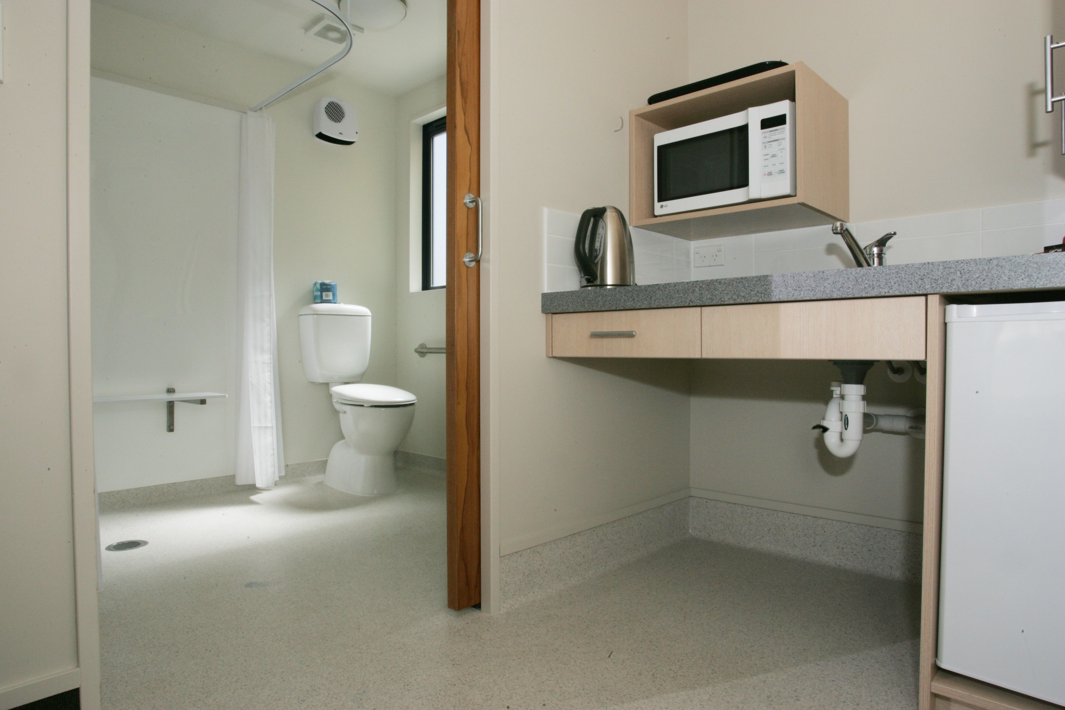 Un baño pequeño con inodoro, lavamanos y microondas.