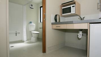 Un baño pequeño con inodoro, lavamanos y microondas.
