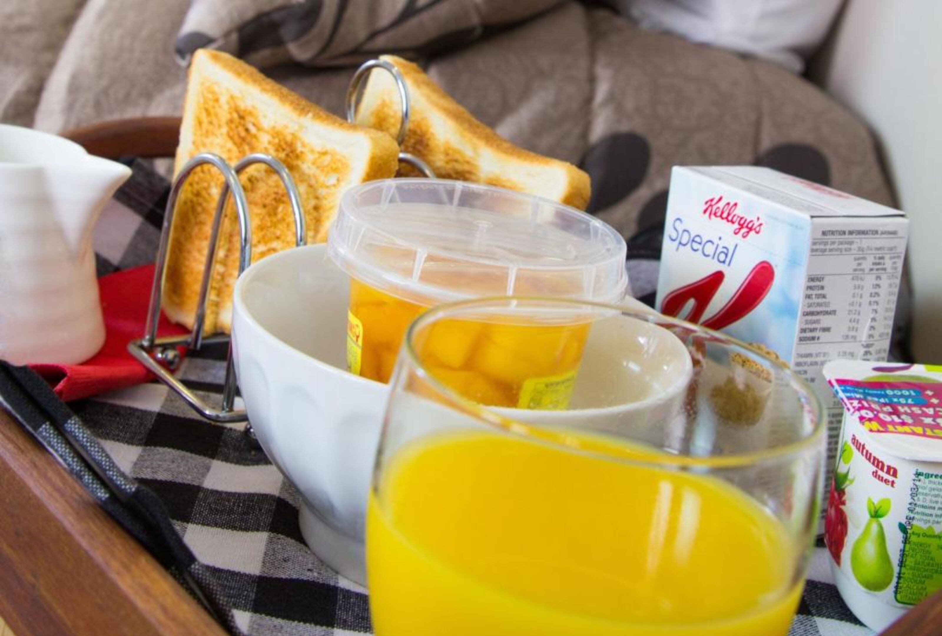 Un plateau de petit-déjeuner avec des toasts, un verre de jus d’orange, une tasse de café et une boîte de céréales Kellogg’s Special K.