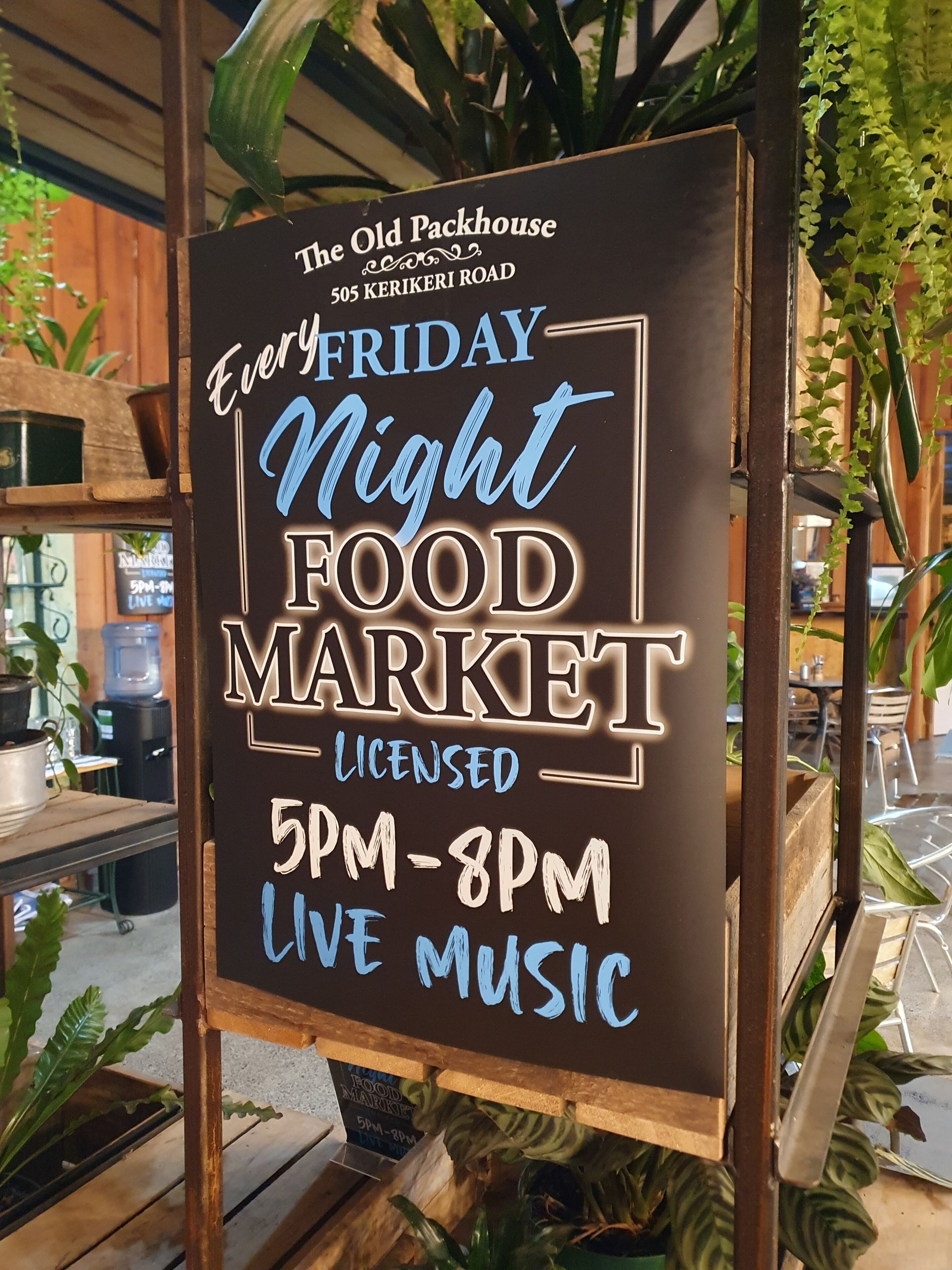 A sign for The Old Packhouse food market, located at 505 Kerikeri Road, open every Friday from 5 PM to 8 PM with live music.