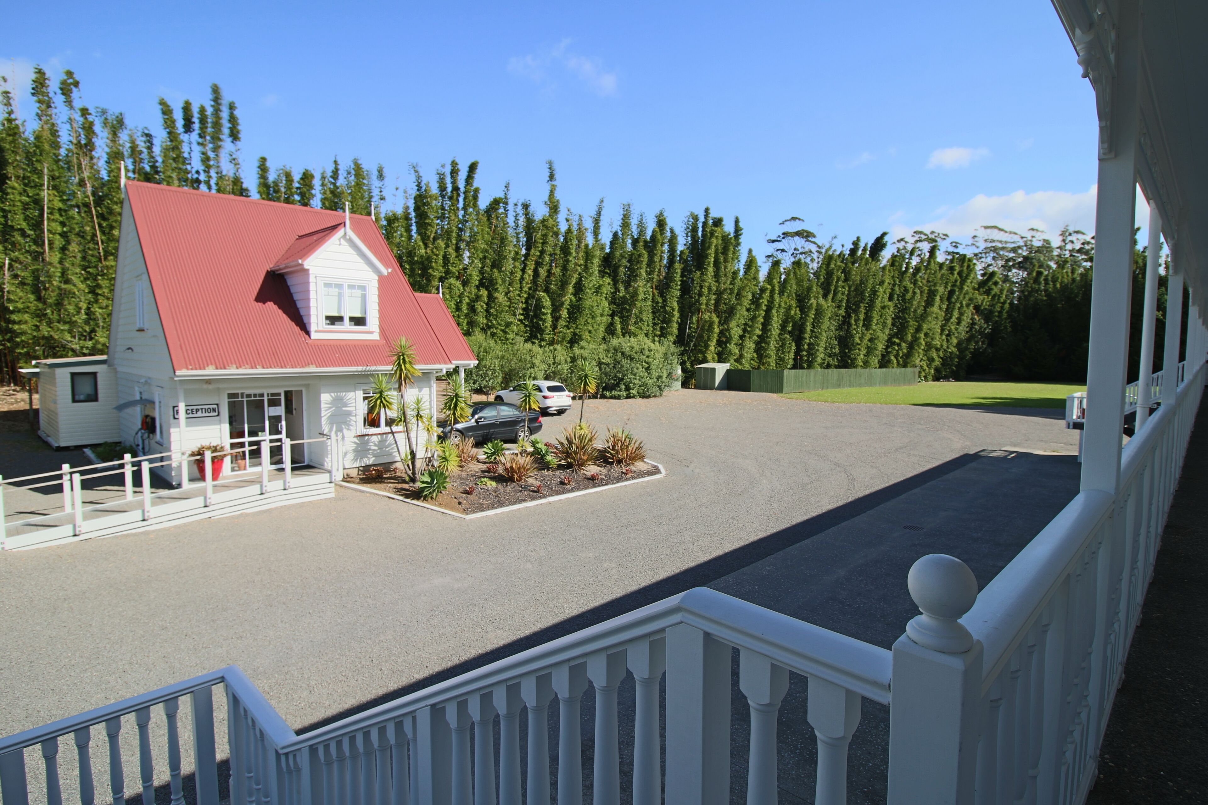 A two-story building with a red roof, a reception area, and a parking lot with cars and landscaping.