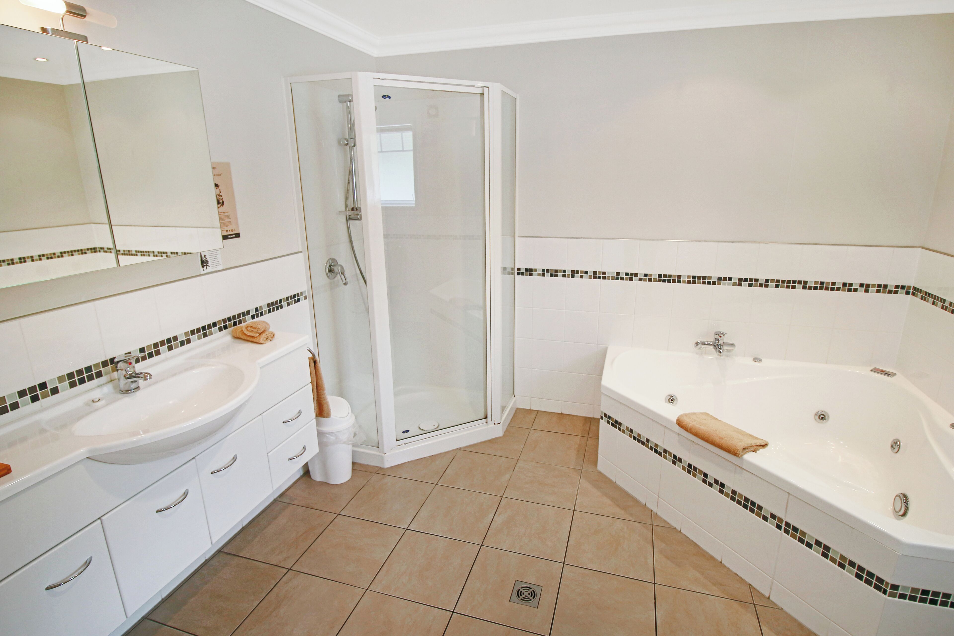 A modern bathroom with a sink, mirror, shower, and bathtub.