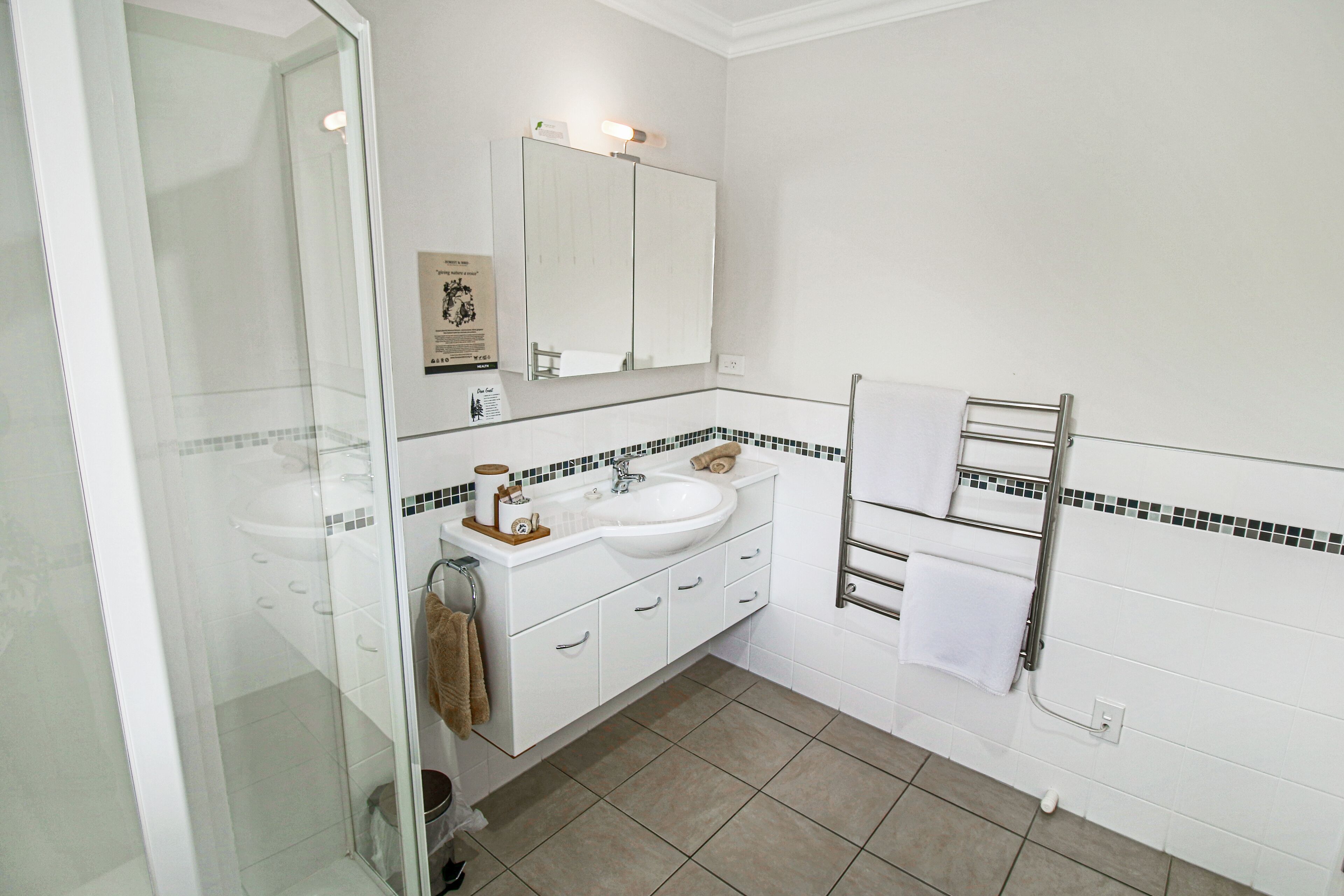 Un baño moderno con cabina de ducha de vidrio, un lavabo blanco y un espejo encima.