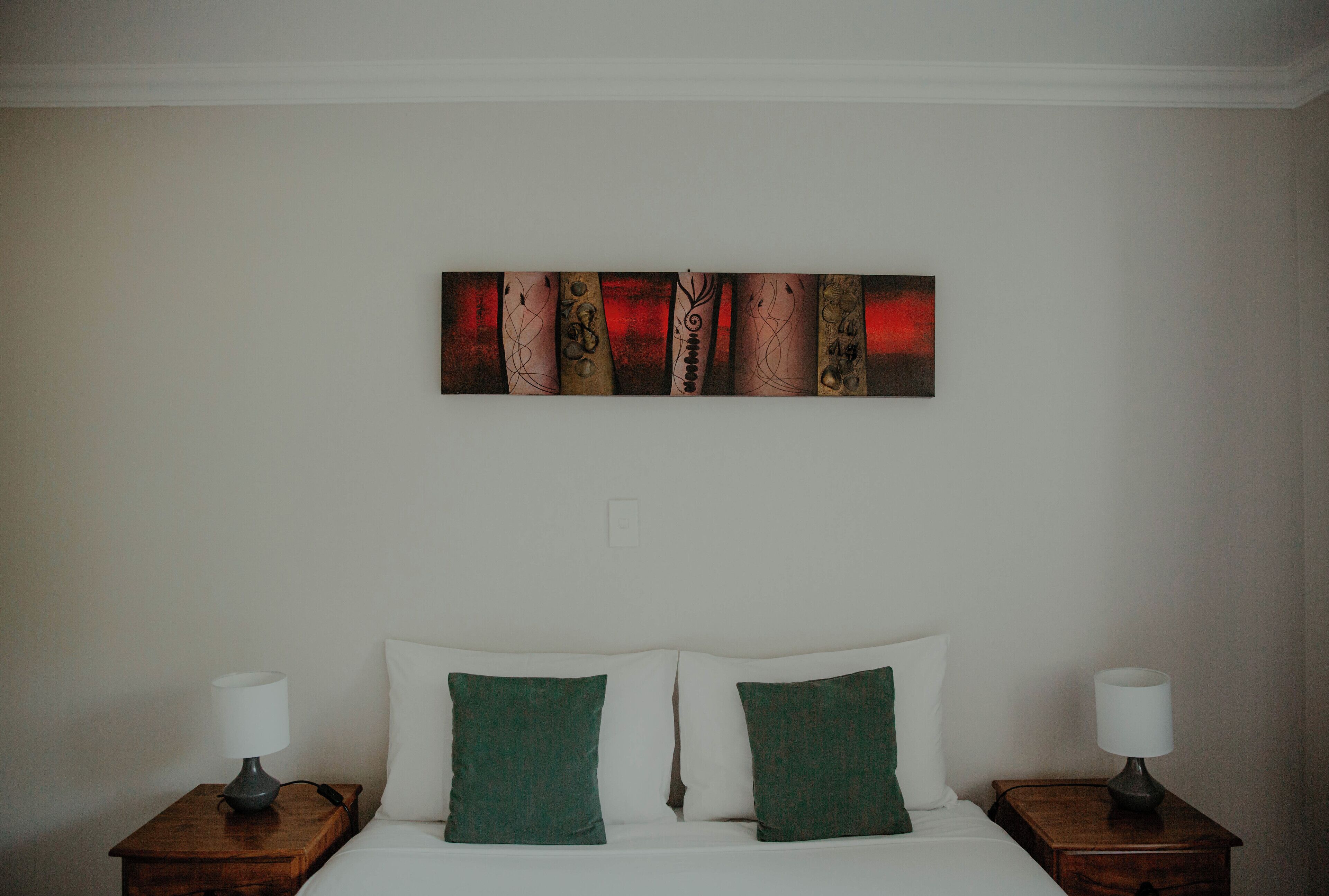 A hotel room with a bed, two nightstands, and a wall-mounted artwork.