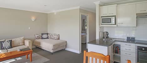 A compact living space with a kitchenette, a sofa, a dining table, and a coffee table.