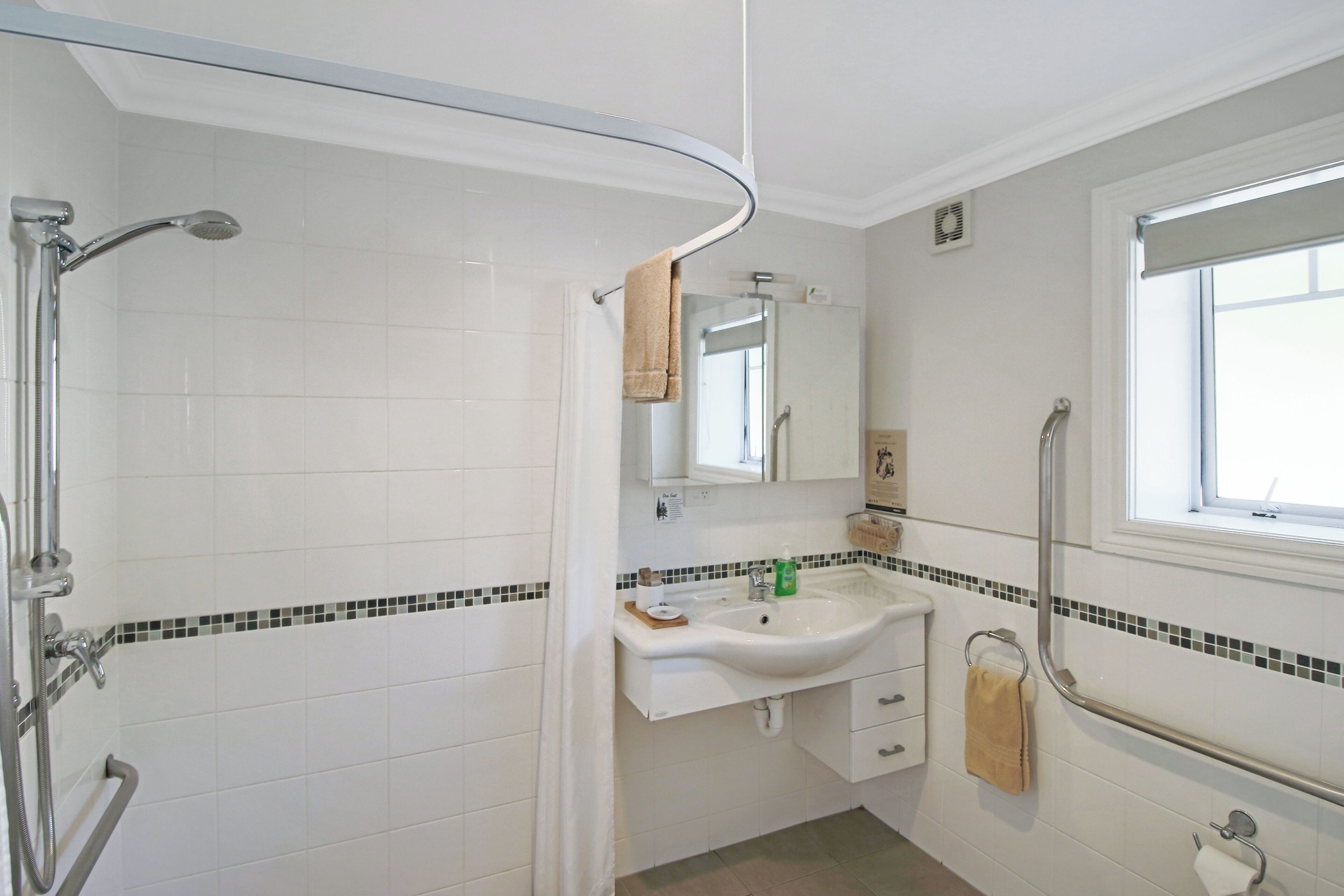 Une salle de bain avec une douche, un lavabo et un miroir.