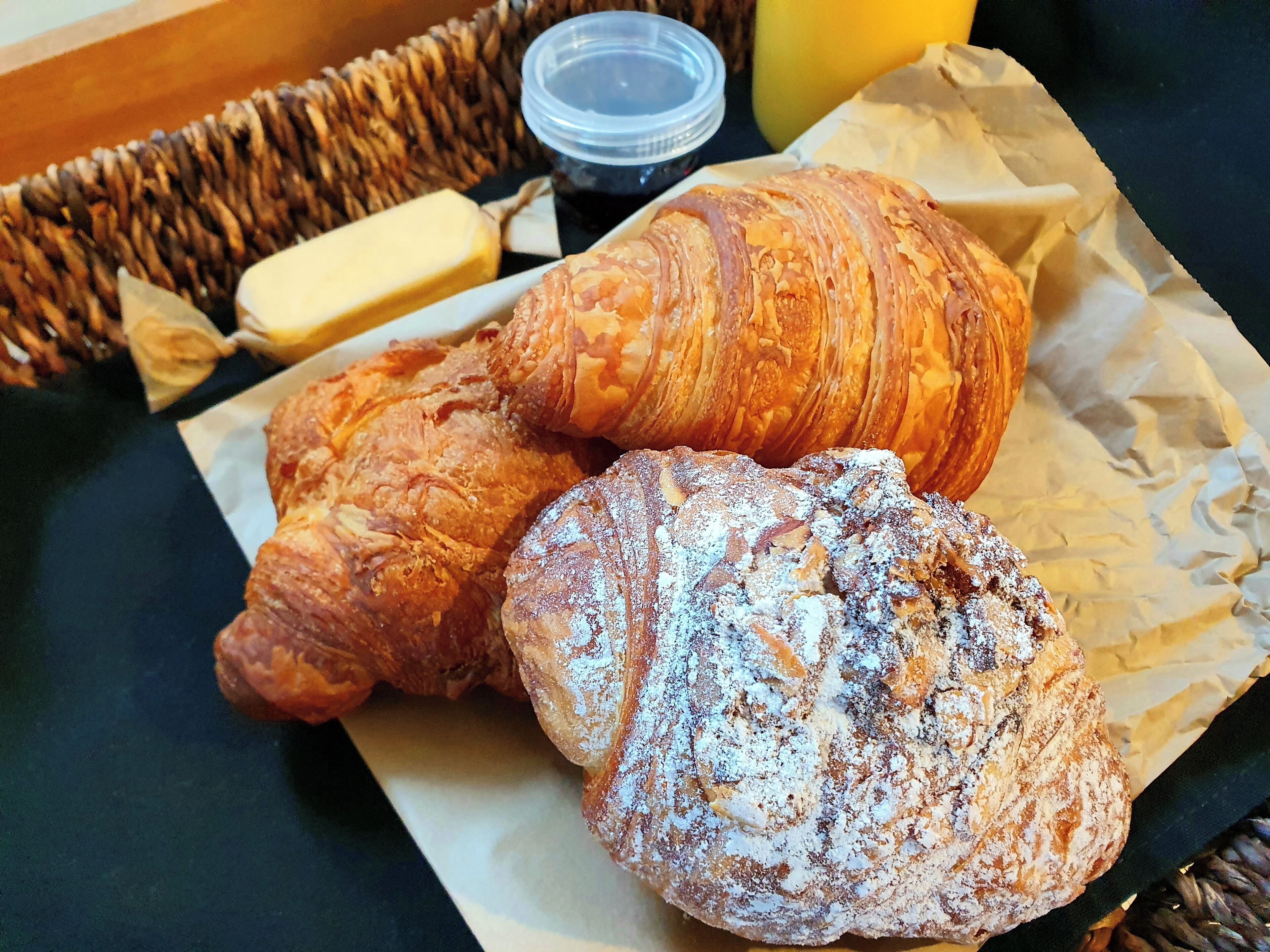 A table with three pastries, a container of butter, and a small jar.