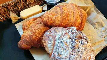 A table with three pastries, a container of butter, and a small jar.
