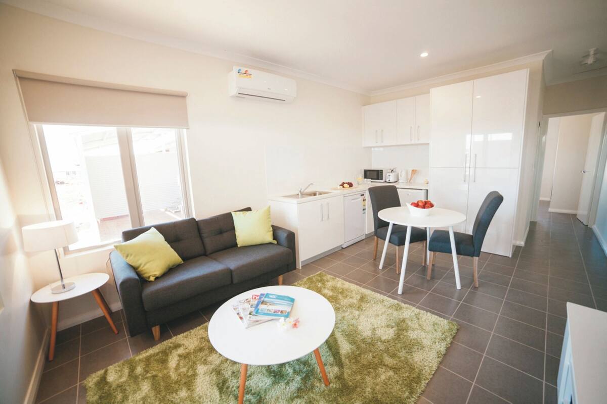 Una sala moderna con un sofá, una mesa de centro y un comedor con una silla y una mesa.