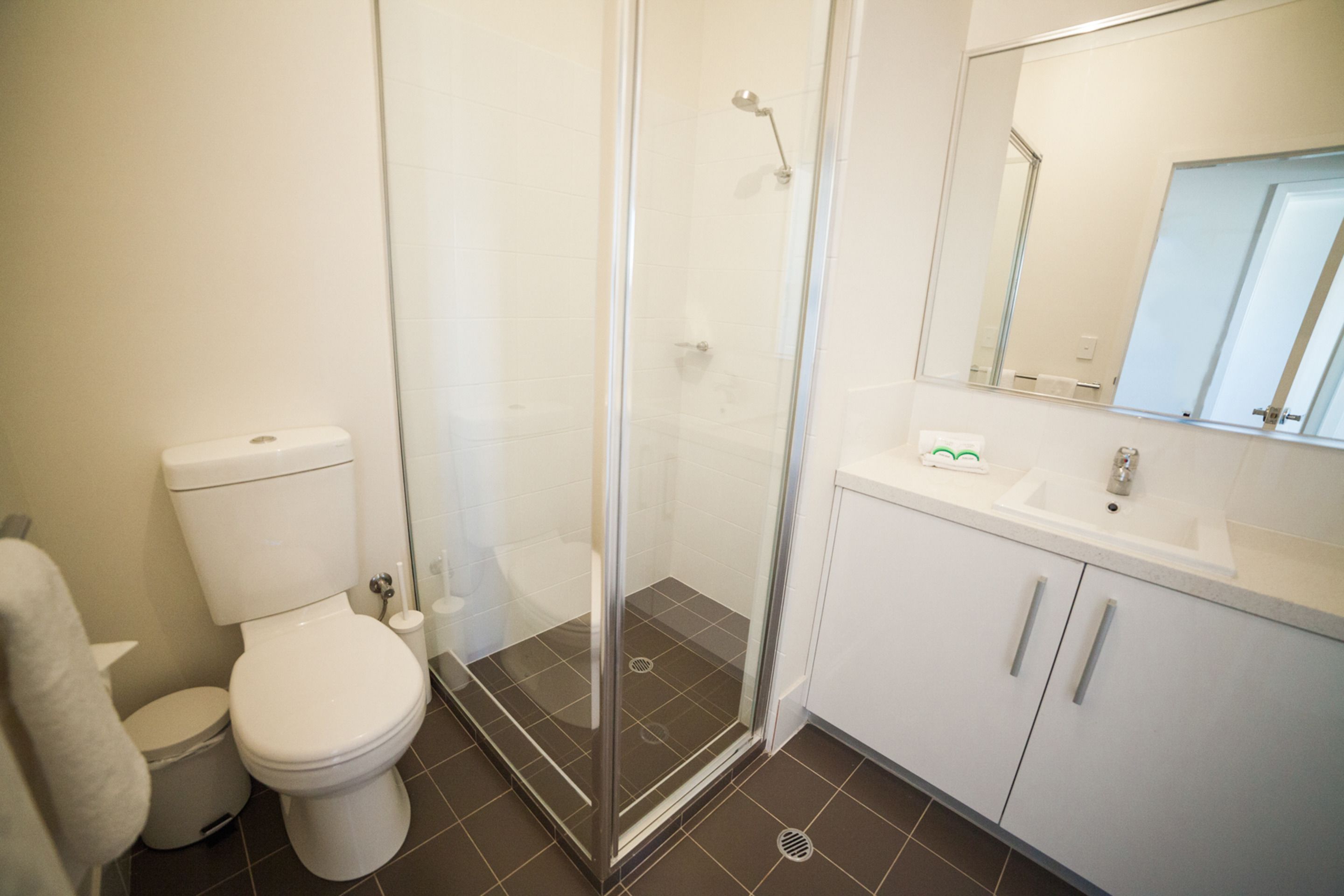 A bathroom with a toilet, a shower enclosure, and a sink with a mirror.
