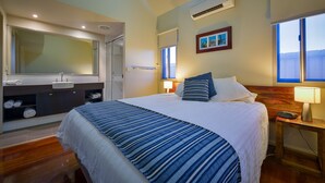 A hotel room with a large bed, a bathroom with a sink and mirror, and a window with a view. - Exmouth Escape Resort (Exmouth)